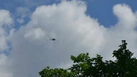 A helicopter hovers motionless in sky against a backdrop of large white clouds Stock Footage 318922911