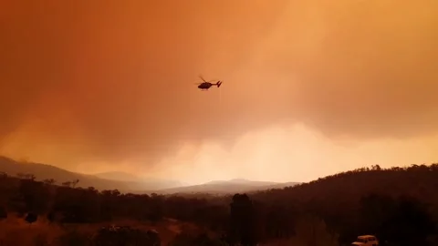 A Helicopter Hovers In Orange Bushfire Clouds Stock Footage 195281248