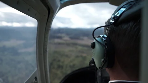 Helicopter interior behind pilot looking out at countryside scenery Stock Footage
