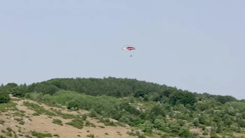 A helicopter on its way to drop water on a developing forest fire near Rocca di Stock Footage 341133928