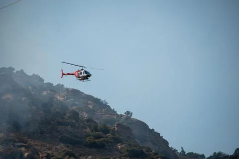 A helicopter from the LAFD performs a water drop and observation during a bru Stock Photos