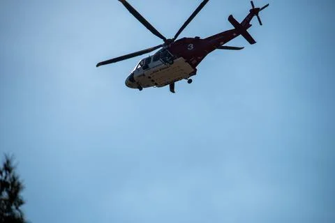 A helicopter from the LAFD performs a water drop on burning brush through smo Foto stock