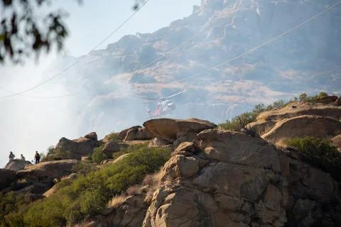 A helicopter from the LAFD performs a water drop on burning brush near firefi Stock Photos