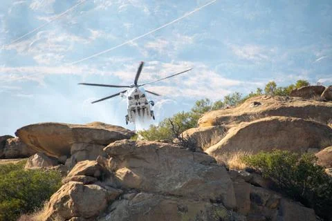 A helicopter from the LAFD performs a water drop on burning brush near firefi Stock Photos