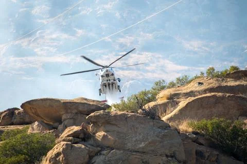 A helicopter from the LAFD performs a water drop on burning brush near firefi Foto stock