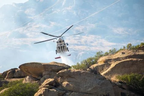A helicopter from the LAFD performs a water drop on burning brush near firefi Foto stock