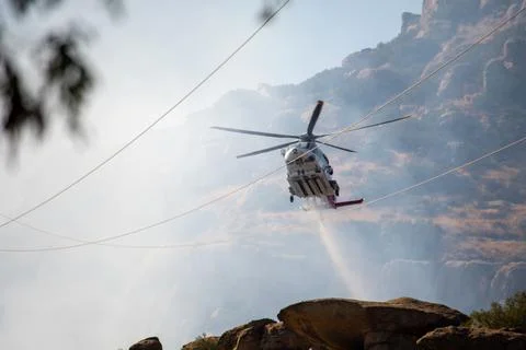 A helicopter from the LAFD performs a water drop on burning brush near firefi Foto stock
