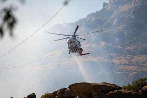A helicopter from the LAFD performs a water drop on burning brush near firefi Foto stock