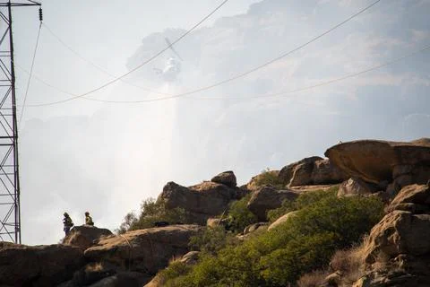 A helicopter from the LAFD performs a water drop on burning brush near firefi 스톡 사진