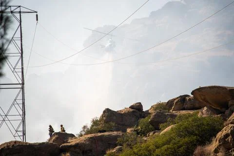 A helicopter from the LAFD performs a water drop on burning brush near firefi Foto stock