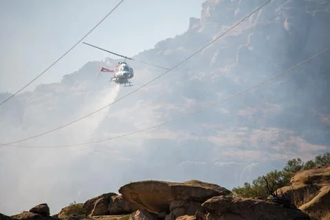 A helicopter from the LAFD performs a water drop on burning brush near firefi Foto stock