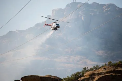 A helicopter from the LAFD performs a water drop on burning brush near firefi Stock Photos