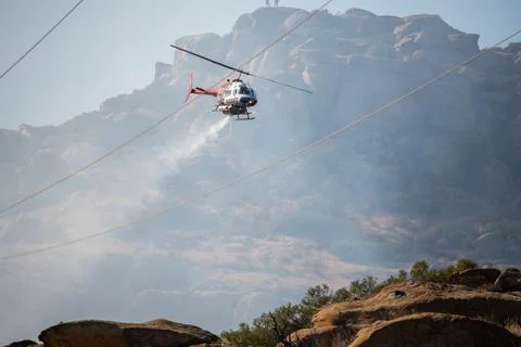 A helicopter from the LAFD performs a water drop on burning brush near firefi Stock-Fotos