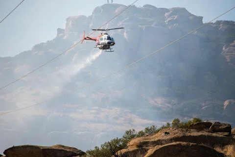 A helicopter from the LAFD performs a water drop on burning brush near firefi Stock Photos