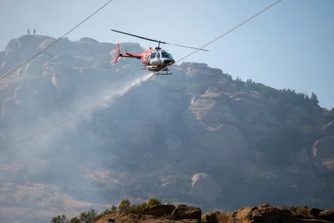 A helicopter from the LAFD performs a water drop on burning brush near firefi Foto stock