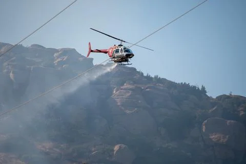 A helicopter from the LAFD performs a water drop on burning brush near firefi Foto stock