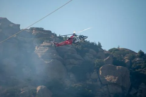 A helicopter from the LAFD performs a water drop and observation during a bru Foto stock