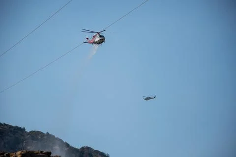 A helicopter from the LAFD performs a water drop and observation during a bru Stock Photos