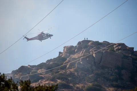 A helicopter from the LAFD performs a water drop near firefighters at a brush Stock Photos