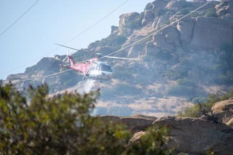 A helicopter from the LAFD performs a water drop near firefighters at a brush Stock Photos