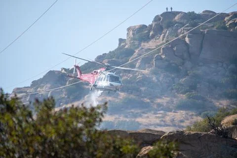 A helicopter from the LAFD performs a water drop near firefighters at a brush Foto stock