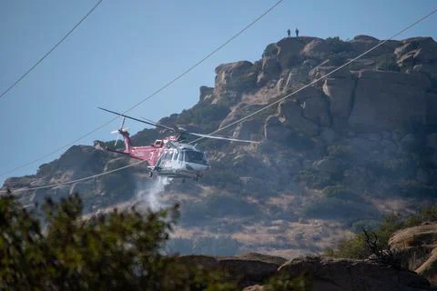 A helicopter from the LAFD performs a water drop near firefighters at a brush Stock-Fotos