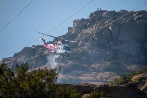 A helicopter from the LAFD performs a water drop near firefighters at a brush Foto stock