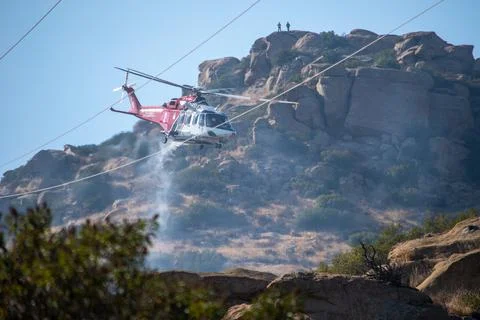 A helicopter from the LAFD performs a water drop near firefighters at a brush Foto stock