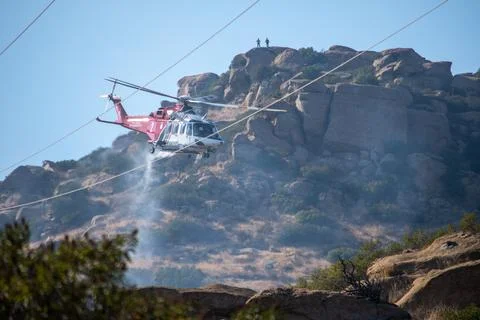 A helicopter from the LAFD performs a water drop near firefighters at a brush Stock-Fotos