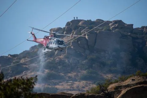 A helicopter from the LAFD performs a water drop near firefighters at a brush Stock Photos