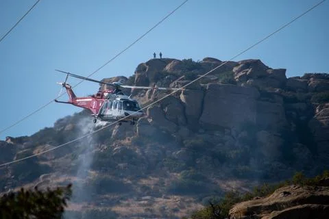 A helicopter from the LAFD performs a water drop near firefighters at a brush Stock-Fotos