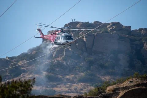 A helicopter from the LAFD performs a water drop near firefighters at a brush Stock-Fotos