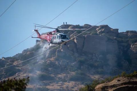 A helicopter from the LAFD performs a water drop near firefighters at a brush Stock-Fotos