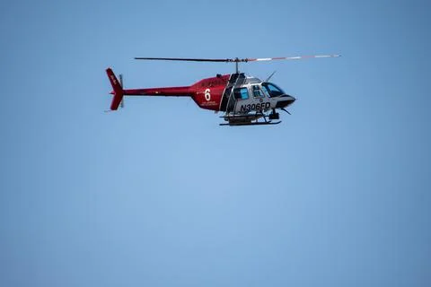 A helicopter from the LAFD performs a water drop and observation during a bru Stock Photos