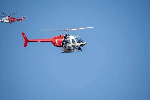 A helicopter from the LAFD performs a water drop and observation during a bru Stock Photos