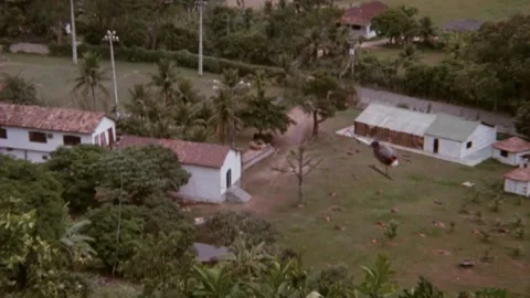 Helicopter leaving compound as house explodes, 1980s Stock Footage 260258607