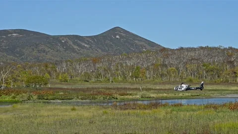 Helicopter is located on background of mountains and green forests in Kamchatka Stock Footage 157230692