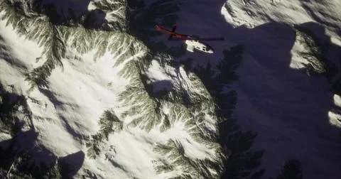 Helicopter navigating through rugged mountain terrain under snow covered peak Ilustração Stock