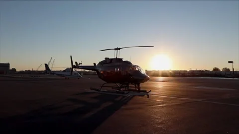 Helicopter parked at a hanger with sun setting and blue sky. Stock Footage 135797614