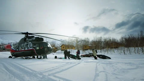 Helicopter Parked on Snowy Field with Crew Loading Gear Vidéo 331667775