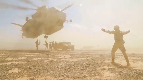 A helicopter picks up artillery and other military gear in the desert. Stock Footage