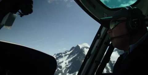 Helicopter Pilot flying inside the helicopter over glacier or snow covered mount Stock Footage 64452333