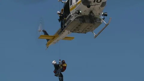 Helicopter pulling firefighters up during rescue training exercise Stock Footage 116469176