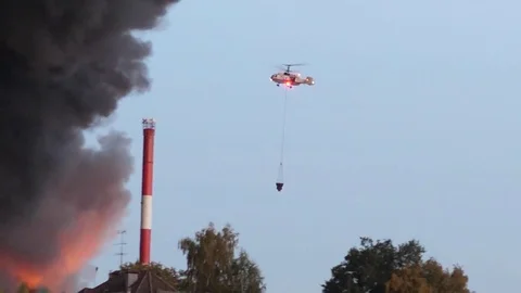 Helicopter is putting out a fire in the city. Helicopter flies into the fire and Stock Footage 80950917