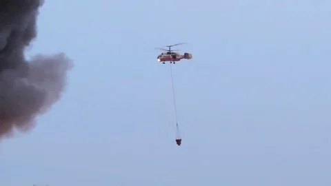 Helicopter is putting out a fire in the city. Extinguishing fire with water from Stock Footage 80950977