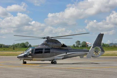 Helicopter ready on runway under cloudy sky Stock Photos