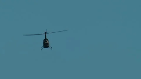 Helicopter rotorcraft flying through a vibrant blue sky, highlighting aerospace Stock Footage 339797934