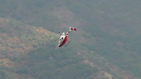 Helicopter Rotorfly R-30 performs aerobatics on blurred background of mountain. Stock Footage 131583622