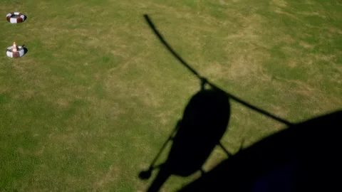 Helicopter shadow glides over green grass field, showcasing the continuous 스톡 동영상 328480868