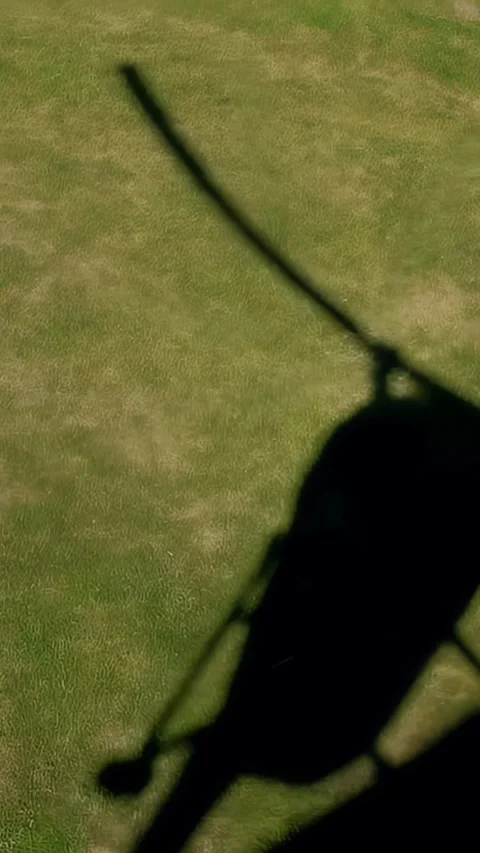Helicopter shadow glides over green grass field, showcasing the transition of Vidéo 329201819